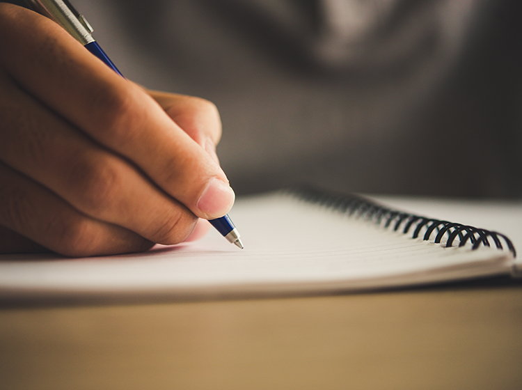 close up of a hand writing on notebook