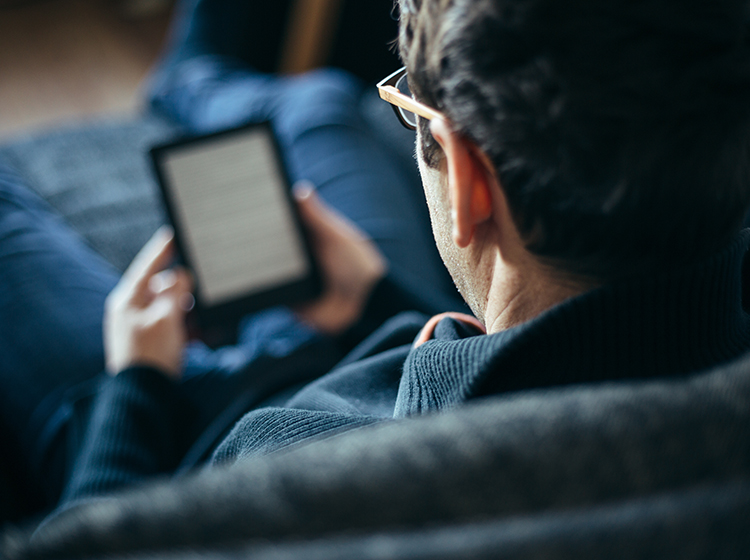man reading from a device on couch 